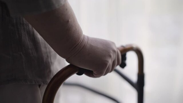 Hands of sick old person holding walking frame, senior age problems, disability