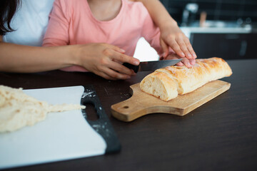 close-up bread knife and hands of mother and daughter in the kitchen.