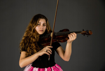 Beautiful young girl with curly hair playing the violin.