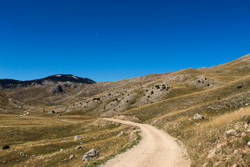 The mountain road and the rocky landscape of the Bjelasnica mountain. In the background, the top of the mountain mountain Bjelasnica.