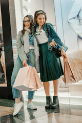 Trade, buyers. Two beautiful girls make purchases in a shopping center, go shopping. The joy of consumption.