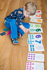Early mathematic. Little boy playing with numbers and dot cards. Home school according to montessori methodology. Intellectual game, preschool implement for early education.