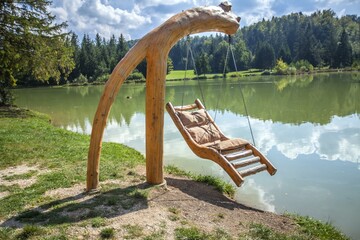 Wooden swing over Lake Bloke in Nova Vas, Slovenia on a sunny day