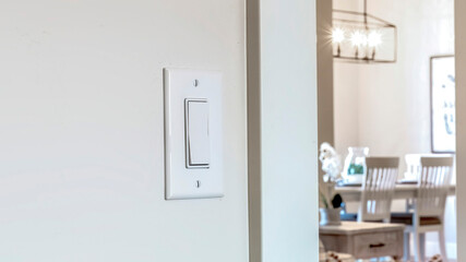 Panorama crop Wall mounted electrical rocker light switch with blurry dining room background