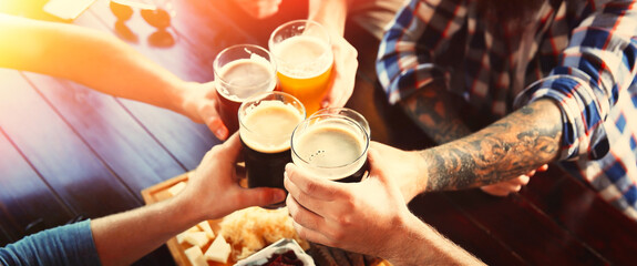 Groep vrienden roosteren met bier in pub, close-up. Bannerontwerp