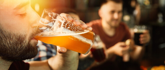 Young man drinking tasty beer in pub, space for text. Banner design