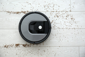Modern robotic vacuum cleaner removing scattered buckwheat from wooden floor, top view - obrazy, fototapety, plakaty