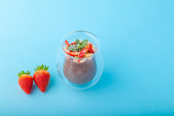 Chocolate Chia pudding decorated with strawberry on blue background
