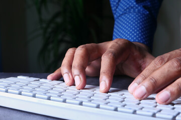 young man typing on keyboard at office desk