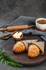 Fresh crispy baked croissants and butter on wooden board
