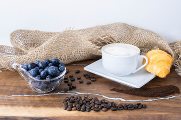 morning coffee with croissant, coffee beans and berries on the table