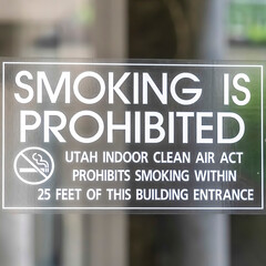 Square Smoking is Prohibited sign close up on clear glass door of building in Utah