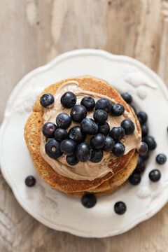 Topview image of the stack of oatmeal pancakes topped with blueberries