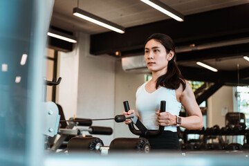 Young beautiful woman in sportswear working out with machine in gym