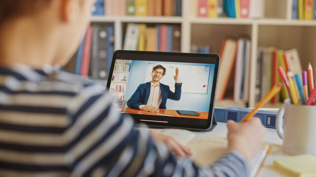 Smart Little Boy Uses Digital Tablet for Video Call with His Teacher. Screen Shows Online Lecture with Teacher Explaining Subject from a Classroom. E-Education Distance Learning, Homeschooling