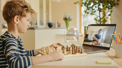 Brilliant Little Boy Playing Chess with His Chess Master, Uses Laptop for Video Call. Remote Online...