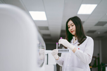 young female scientist insert sample to automation blood analyzer in medical laboratory