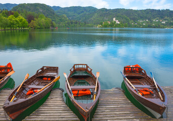 Traditional boats waiting for tourists on Lake Bled, with the lake island and charming little church in the background, famous tourists attraction in Slovenia