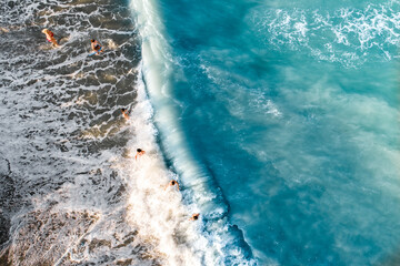 Drone view of group of children playing in the sea waves, kids getting hit by wave 
