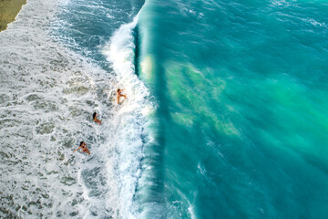 Fototapeta premium Drone view of group of children playing in the sea waves, kids getting hit by wave 