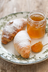 Croissants on a white plate with green ornament served with oran