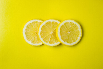 Three slices of lemon lie on top of each other on a yellow background. Round slices of lemon. Photo above