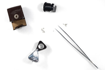 A diamond appraisal. Tools for evaluation of diamonds (magnifier, measuring loupe, tweezers) isolated on white background.