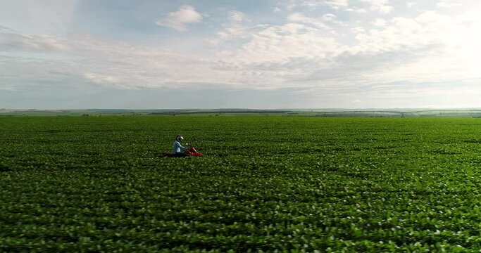 Agribusiness - Aerial image Farmer inspects the growth of soybeans riding a motorcycle through the countryside. Green soy field. Technology in the field. - Agriculture