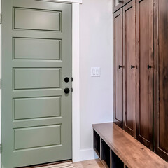 Square crop Panelled fire door with black knobs and lock adjacent to a tall vintage cabinet