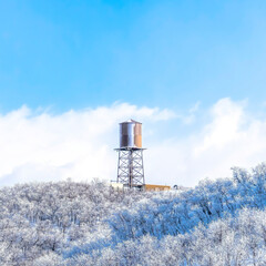 Square frame Wasatch Mountains landscape with water tank tower on the snowy slope in winter
