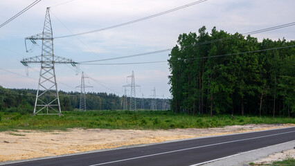 Fototapeta na wymiar Asphalt road on the background of electric poles with wires and woods.