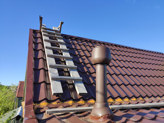 A wooden ladder on the roof with a chimney