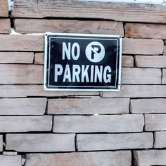 Fototapeta premium Square No Parking sign on a stone brick retaining wall topped with snow in winter