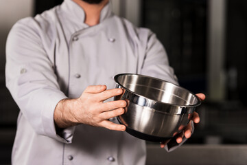 Chef hand keep bowl. Closeup chef hands demonstrate steel bowl.
