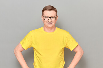 Portrait of happy mature man with glasses, wearing yellow T-shirt