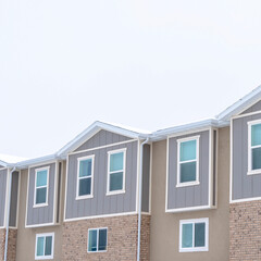 Square Upper storey of townhomes with snowy pitched roofs on a cold winter day