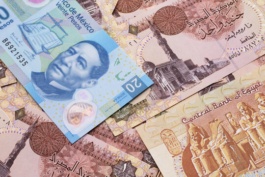 A close up image of a blue, twenty Mexican peso note on a bed of brown, one pound notes from Egypt
