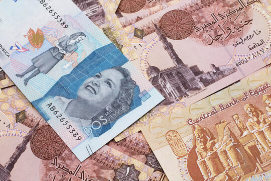 A close up image of a blue two thousand Colombian peso bank note on a background of Egyptian one pound bank notes in macro