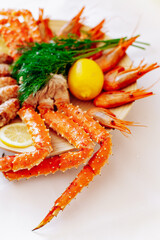 Red king crab and shrimp on a plate with lemon and dill. White background