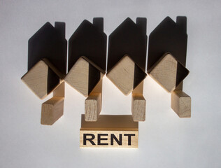 Houses created by shadows from wooden cubes. The word 'rent' on a wooden block.