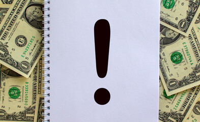 White note with exclamation point on beautiful background from dollar bills. Concept. Copy space.
