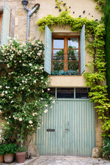 Façade d'une maison décorée par des rosiers en fleurs. Provence, France.  - 357895744