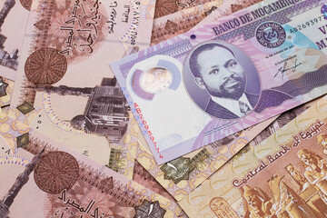 A close up image of a purple, twenty metical bank note from Mozambique on a background of Egyptian one pound bank notes
