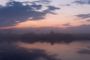 Fototapeta premium Purple sunset over a small river and reflection of the sky in the water.