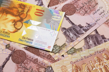 A yellow, ten Swiss franc note from Switzerland close up in macro with Egyptian one pound bank notes