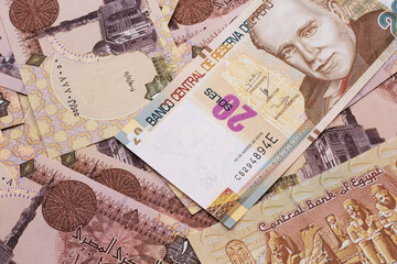 A close up image of a new, Peruvian twenty sol bank note close up on a bed of Egyptian one pound bank notes in macro