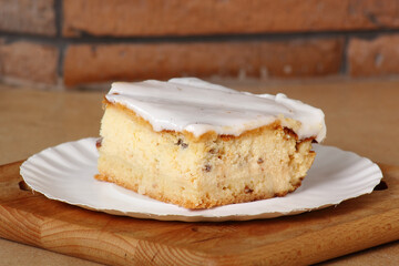 Cheesecake on disposable paper plate. Cheesecake with raisins topped with sugar icing.