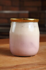 Yogurt in small glass jar with aluminium foil seal cap. Macro. C