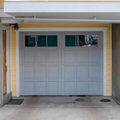 Square Snowy home with gray glass panelled garage door and stairs going to porch