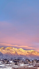 Fototapeta na wymiar Vertical Homes on snowy hill against frosted Wasatch Mountain with golden glow at sunset